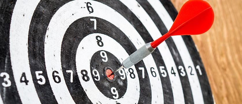 Rote Dartpfeil steckt im Zentrum einer schwarz-weißen Dartscheibe