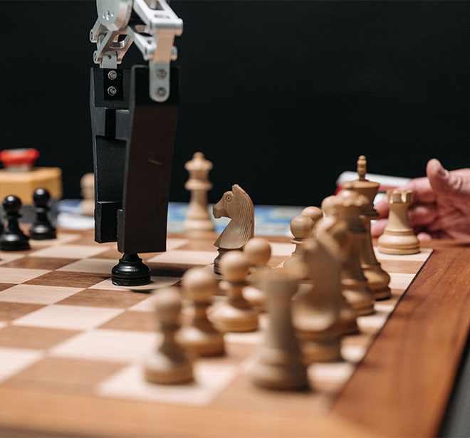 BrandTrust Webinar "Markenrelevanz sichern: Der Fahrplan für die KI-Ära" BrandTrust Webinar zu "Markenrelevanz sichern: Der Fahrplan für die KI-Ära" - passend dazu ein Schachbrett aus Holz, auf dem auch ein Roboterarm und eine menschliche Hand zu sehen sind.