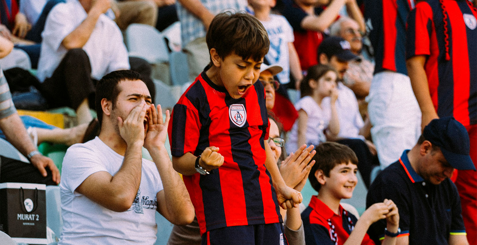 Starke Communitys: Was Marken von Sportvereinen lernen können - Auf dem Foto sieht man jubelnde Fans, im Vordergrund ein Kind