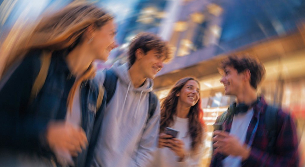 Vier Personen, die der Generation Z angehören, reden miteinander und haben Handys in der Hand - passend zum Whitepaper 'Die Gen Z leichter gewinnen'